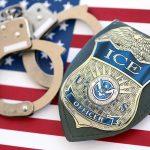 ICE officer badge and handcuffs on an American flag