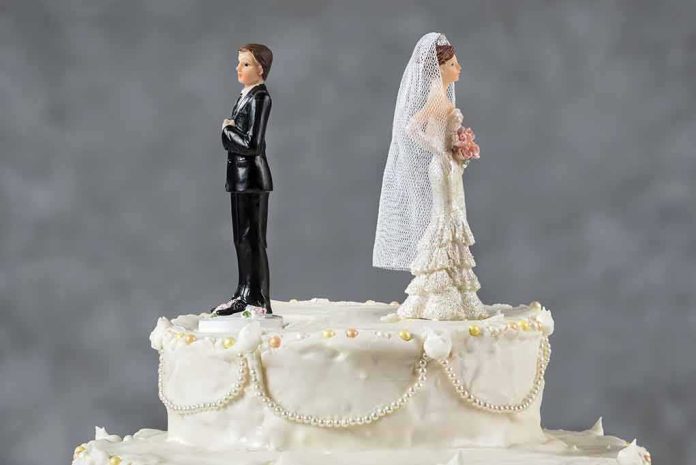 Bride and groom figurines facing away on top of a white wedding cake
