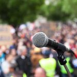Amy Acton ‘Attack’ Story Gets a MAJOR Update microphone on stand in front of a blurred crowd