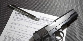 Handgun on firearm transaction form with pen