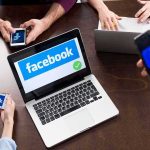 Laptop with Facebook on screen surrounded by smartphones