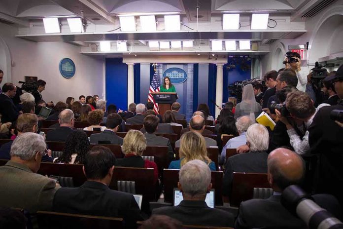 Press secretary at podium addressing reporters in briefing room