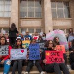 Cornell Scandal Ignites NATIONWIDE Fight Students holding protest signs on school steps
