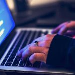 Human FECES Reportedly Found on Library Keyboards hands typing on a laptop with code on screen