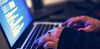 hands typing on a laptop with code on screen