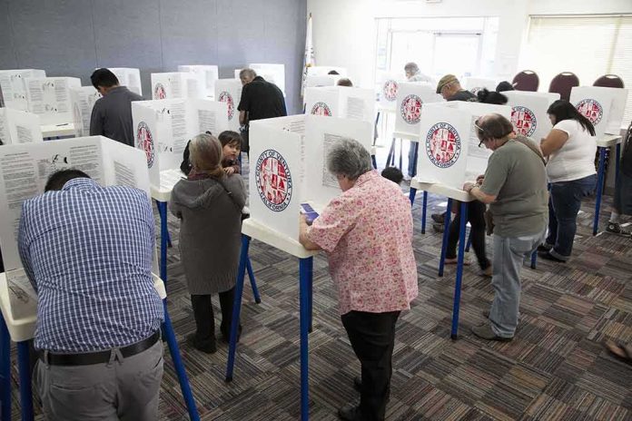 shutterstock_133686017-1 Voters fill out ballots at polling booths in a busy voting room