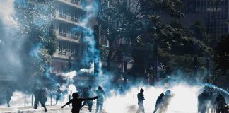 Protesters running through tear gas on a city street