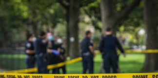 Police Warn High-Risk PREDATOR Is Back on Streets crime scene tape with police officers in a park