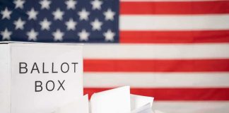 Ballot box with papers in front of an American flag