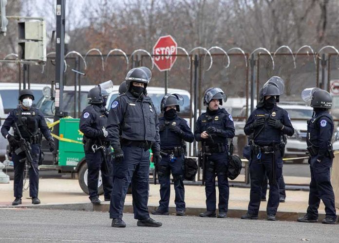 shutterstock_1898881783 Group of police officers in riot gear standing on a street; Brian Folkerts present