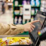 Strong Economy Numbers Hide STRANGE Disconnect Shopper using self-checkout touchscreen in a grocery store