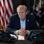 Trump Reportedly Wants Omar to RESIGN Donald Trump seated at a table between two desk phones