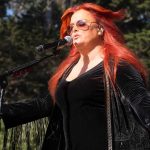 Wynonna Judd Reveals Her VIOLENT Childhood Wynonna Judd singing on an outdoor stage with arms outstretched