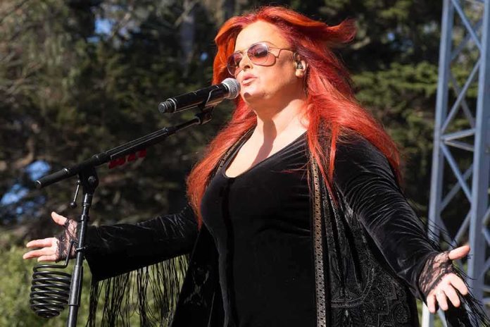 shutterstock_498893284 Wynonna Judd singing on an outdoor stage with arms outstretched