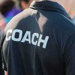 Coach wearing a black shirt with bold lettering
