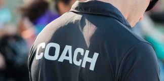 Legendary Coach Kept His Diagnosis SECRET for Months Coach wearing a black shirt with bold lettering