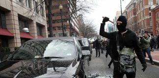 600 French Schools Hit by VIOLENT Protests Masked protester raises tool to strike black car on city street