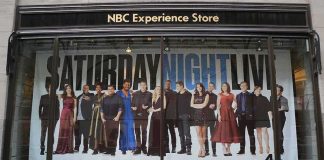 Storefront window with large SNL poster featuring Leslie Jones, Bobby Moynihan, Michael Che, Shirley Ellis, Kenan Thompson, and Richard Z. Kruspe