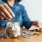 Person adding coins to a savings jar