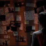 Person examining a bulletin board with documents and photos.