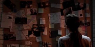Person examining a bulletin board with documents and photos.