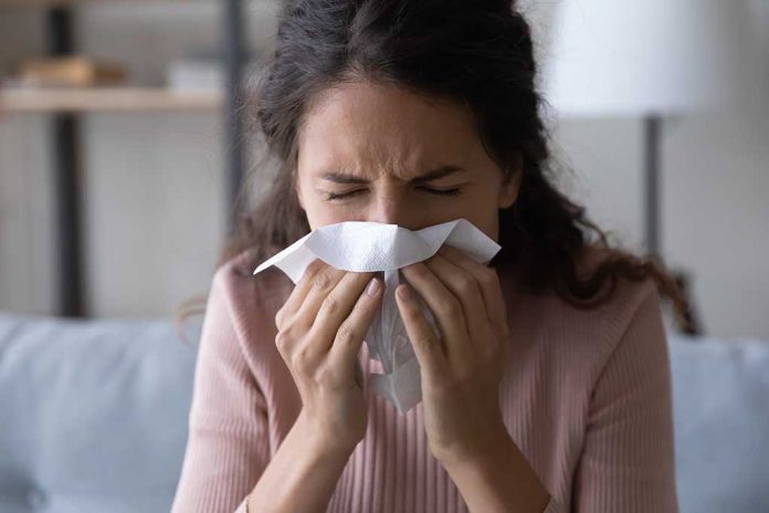 1906128409 featured image Woman sneezing into a tissue indoors.