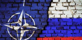 NATO logo and Russian flag painted on brick wall.