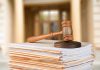 Gavel resting on stack of paperwork in courtroom.