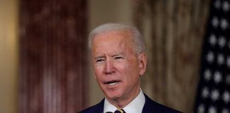 Man speaking at podium with microphones indoors