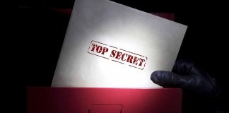Gloved hand holding top secret document in file drawer