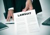 Person holding a document labeled Lawsuit.