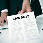 Person holding a document labeled Lawsuit.