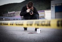 Person photographing crime scene evidence behind police tape