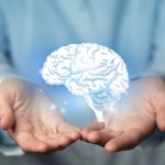 Hands holding a holographic brain visualization