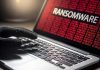 Gloved hand on laptop with ransomware screen