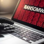 Gloved hand on laptop with ransomware screen
