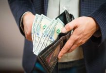 Hands holding wallet with multiple dollar bills