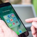 Person holding phone with social media app icons