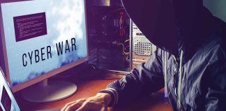Hacker typing at desk with Cyber War screen