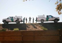 Border Patrol vehicles and agents on a ridge