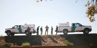 Border Patrol vehicles and agents on a ridge