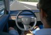 Person in Tesla car using autopilot on highway.