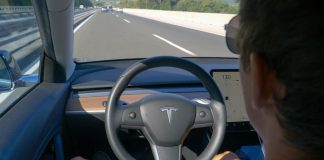 Person in Tesla car using autopilot on highway.