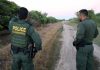 Two Border Patrol officers observing a dirt path