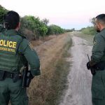 Two Border Patrol officers observing a dirt path