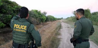 Two Border Patrol officers observing a dirt path