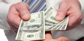 Two hands exchanging cash bills in a business context