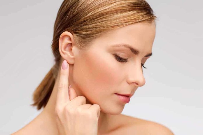 shutterstock_174909794.jpg Profile view of a woman gently touching her ear with a thoughtful expression