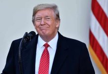 Man in suit and tie speaking at podium
