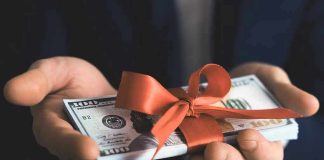 Hands holding stack of hundred-dollar bills with ribbon